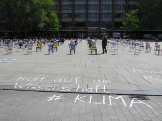 Auf dem Platz der alten Synagoge sind Stühle aufgestellt. Auf den Boden wurde eine Kreidebotschaft gemalt.