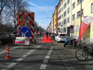 Ein Fahrradfahrer radelt auf dem Roten Teppich, der als Verlängerung eines Fahrradschutzstreifens ausgerollt wurde.