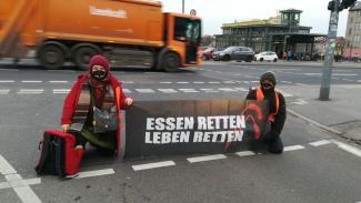 Aktivistiy mit Banner "Essen retten, Leben retten"