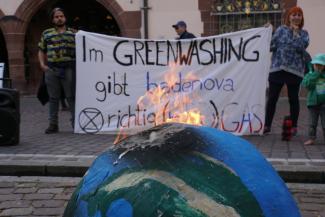 Brennende Erde vor Banner mit Schriftzug "Im Greenwashing gibt Badenova richtig (Erd-)Gas