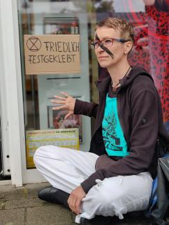 Aktivistin hat sich an Fensterscheibe geklebt.