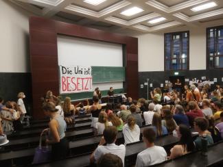 Im Hörsaal hängt ein Banner "Die Uni ist besetzt"