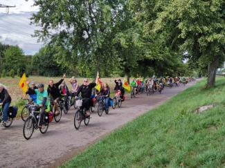 Menschen radeln mit Bannern auf einem Fahrradweg